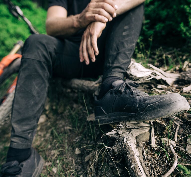Man sitting on the side of a mountain bike trail.