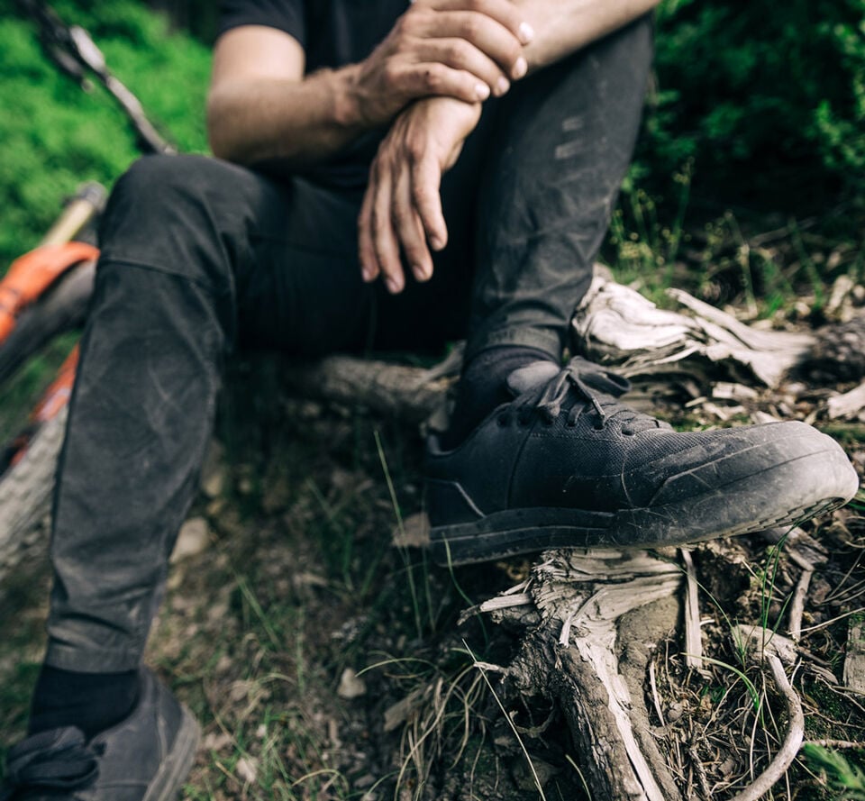 Man sitting on the side of a mountain bike trail.
